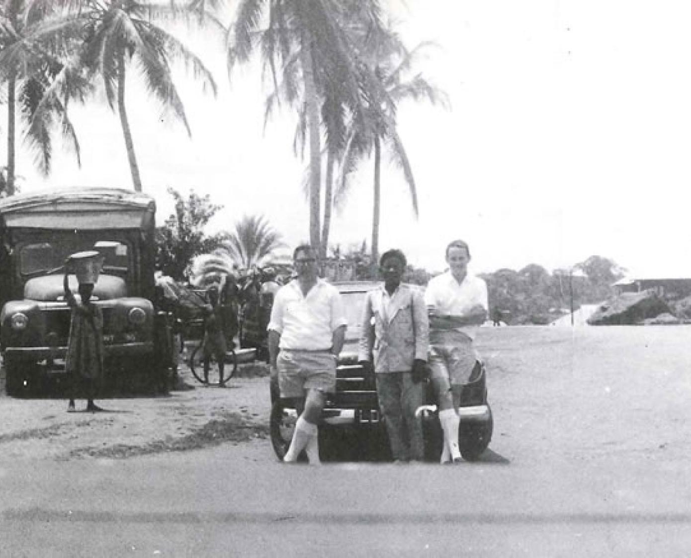 An old photo depicting Knight Franks move abroad, featuring a group of men stood by a car near some palm trees